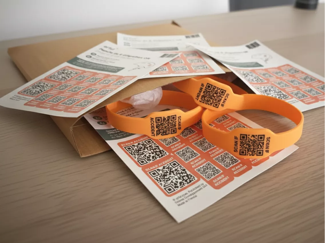 Stickers QRful et bracelets QR orange étalés sur une table, prêts à être utilisés ou distribués pour l’identification et la sécurité.